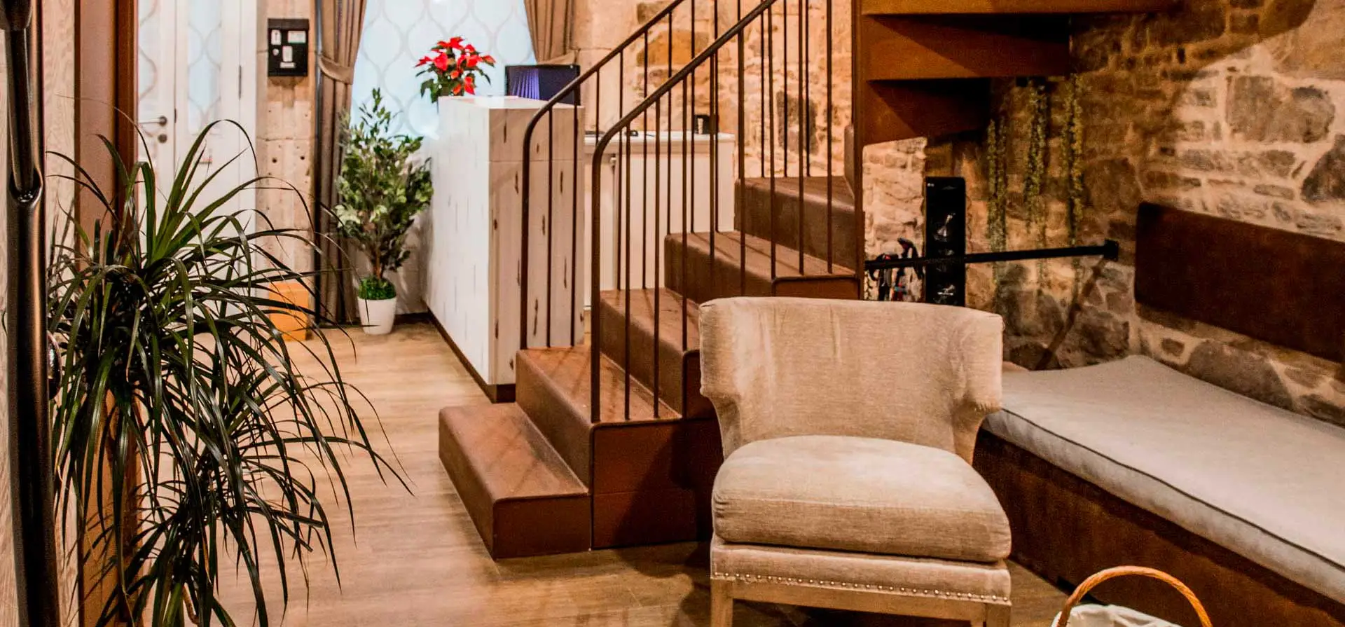 Recepción de la casa con muro de piedra, escalera de madera y un sillón